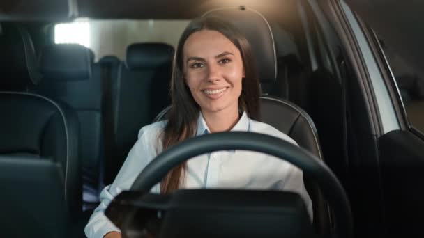 カメラの笑顔を笑顔に微笑む幸せな喜びは 新しいレンタルラグジュアリーモダンカーガール女性ドライバーの自動車運転自動車輸送ビジネスマン女性駐車場で — ストック動画