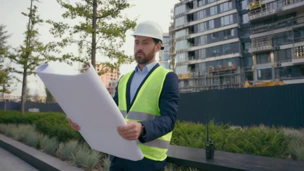 청사진 서류상 계획을 도시에 남자는 헬멧과 조끼에 건축술 엔지니어를 검사하는 — 비디오