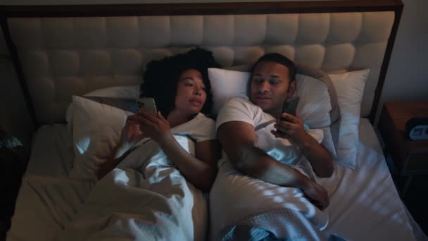 アフリカ系アメリカ人のカップル 夜遅くにベッドで寝る ゲームベッドルームでリラックス ソーシャルメディア スマートフォン ニュースファミリー — ストック動画