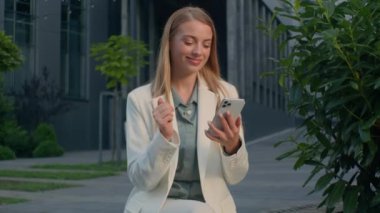 Kafkas kadın iş kadını kadın işkadını e-posta mesajlarını kontrol eden açık hava telefonu kullanarak akıllı telefondan iyi haberler okuyarak onaylanmış jest onaylama anlaşması imzası mükemmel bir sonuç veriyor.