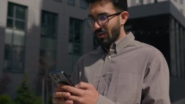 Şaşırmış adam Arap Hintli şanslı işadamı dışarıda cep telefonu şokunu kullanan işveren şehirde online zafer akıllı telefonu kazanarak inanılmaz bir başarı elde etti.