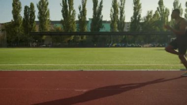 Afrika kökenli Amerikalı sporcu dışarıda diz egzersizi yapıyor. Şehir stadyumunda tek başına koşan sporcu koşucu idmanı. Güçlü bir atlet. Hipodromda koşuyor.