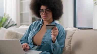 Afrikalı Amerikalı düşünceli müşteri kadın alıcı düşünceli kadın alıcı. Düşünen kız laptop bilgisayar ve banka kredi kartıyla alışverişe karar veriyor. İnternetten satın alınan malların evde alındığını düşünüyor.