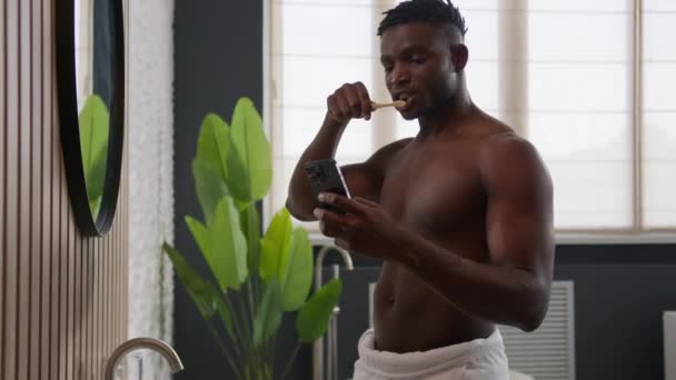 Banyosunda Diş Fırçalayan Cep Telefonunu Kaydıran Afro Amerikalı Bir Adam — Stok video