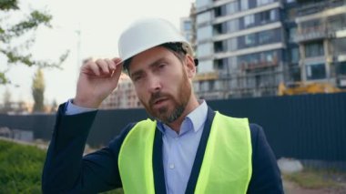Yorgun müteahhit Kafkasyalı orta yaşlı müfettiş müteahhit müteahhit mühendis mimar koruyucu miğfer gülen kaskı alın iş günü şehir binalarını teftiş edin.