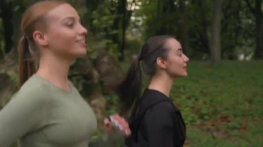 Spor yapan kadınlar, spor yapan kızlar, sağlık tatbikatı için sabah koşularına parkın dışında koşuyorlar. Aktif spor yaşam tarzı, beyaz kadın koşucular, şehrin dışında birlikte koşuyorlar.