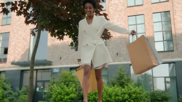 ハッピー笑顔満足のアフリカ系アメリカ人女性スタイリッシュなファッショナブルなガールのお客様買い物客は 薄い舗装バランスショッピングバッグで市内を歩いています コマース割引 ブラックフライデー — ストック動画