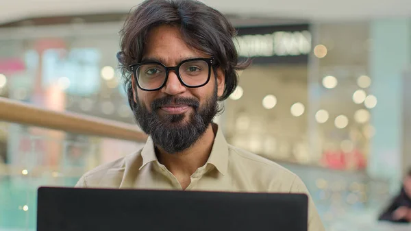 Indian Arabian bearded business man entrepreneur in glasses with laptop showing thumb up good idea support satisfied with good online service male professional businessman happy with using computer