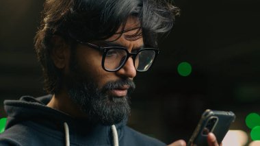 Karanlık otoparktaki Hintli adam şok oldu. Cep telefonu mesajıyla hayal kırıklığına uğradı. Kötü haber Arap erkek adam.