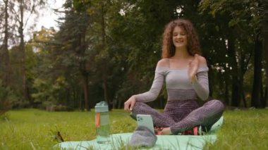 Beyaz kadın etkeni dışarıda parkta kayıt altında video blogunda video blogu çevrimiçi canlı yayın spor eğitmeni kız blogcu fitness yoga minderi üzerinde merhaba antrenör konferansı akışı