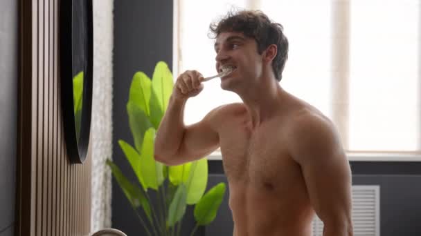 白种人赤身裸体肌肉男男子健康男子早操常规程序习惯刷牙刷牙口腔刷牙牙膏健康护理龋预防新鲜呼吸看着镜子 — 图库视频影像