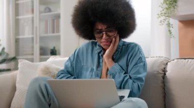 Kafası karışmış Afro-Amerikan kadın kız dizüstü bilgisayarında kötü haberler okuyor. Kanepe kullanıcısı serbest çalışan kadın iş kadını bilgisayar şoku kullanıyor. Stres kullanıyor.
