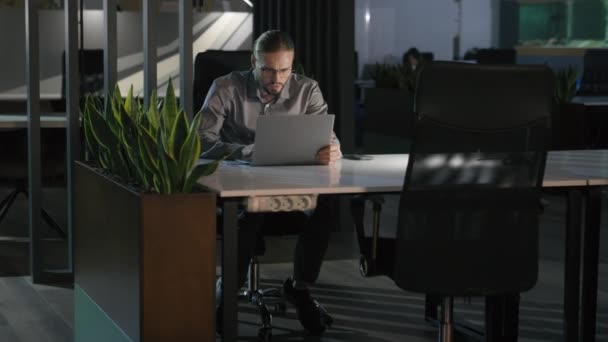 真剣に集中した集中白人ビジネスマン メガネの暗い夜のオフィスのハードワーキングマネージャー 男性の会社のボスジョブ 中毒ビジネスマン ラップトップズームを見ている遅い時間働くコンピュータの仕事 — ストック動画