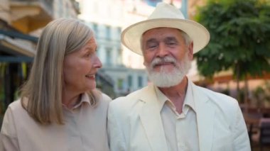 Gülümseyen Kafkasyalı mutlu aile yaşlısı çift zarif erkek erkek kadın kadın emekli kadın turistler şehir kafeteryasında yürüyen turistler emeklilik evliliği tatilleri dışında sohbet ediyorlar.