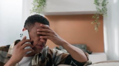 Afrikalı üzgün, stresli, cep telefonuna cevap veren erkek. Hayal kırıklığı yaşayan, stresli, cep telefonu konuşan, akıllı telefon konuşan, kötü haber bankasının iflasını duyan Amerikalı bir adam.