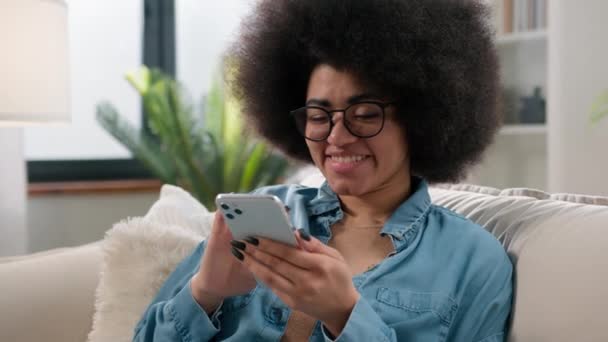 Mutlu Afrikalı Amerikalı Kız Elinde Cep Telefonu Cihazıyla Evinde Gülümseyen — Stok video
