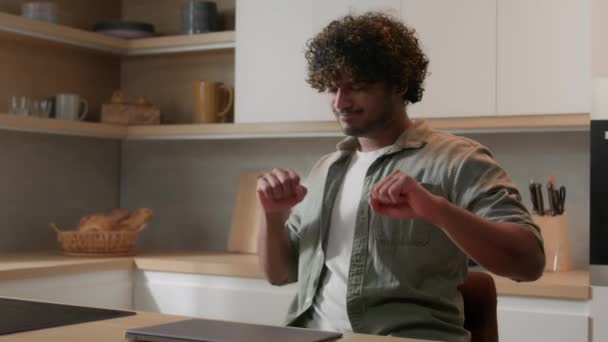 快乐的西班牙男人印度男人喜欢完成一天的工作成功的庆祝网上胜利跳舞听着 音乐庆祝在家里厨房用电脑关闭笔记本电脑完成的工作 — 图库视频影像