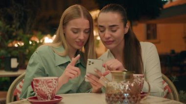 İki Avrupalı Kafkasyalı kadın çay içerken şık kafe telefonla sohbet ederken ukala, kibirli, şüpheci, en iyi arkadaşların dışardaki şehri kınıyor ve dedikodu ifadelerini kınıyor.