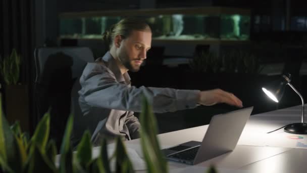 加班加班的商人经理男人在深夜漆黑的办公室结束笔记本电脑的工作关灯台灯离开公司男性完成工作步行回家 — 图库视频影像