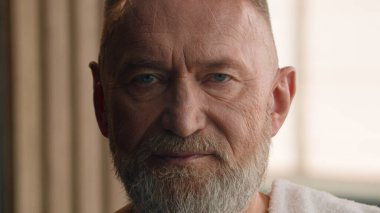 70 'lerin portresi, sağlıklı cilt kırışıklığı, yaşlı büyükbaba gri saç sakalı, saç bakım, makyaj, erkeksi yaşlı erkek, omuzlarında nemlendirici cilt bakımı, banyo havlusu.