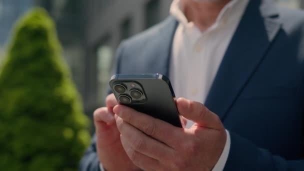 城市退休的中年男人在户外拿着智能手机认真忙碌 体贴的资深商人在城市退休的中年男人在外面打手机看手机新闻 — 图库视频影像
