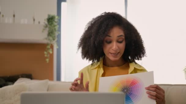 アフリカ系アメリカ人のビジネス女性デザイナーは コンピュータのラップトップ上のオンラインビデオ通話 家のデザインを議論する サンプル色のプレゼンテーション 笑顔のビジネスウーマン クライアントが紙のペイントカラーを選択するのに役立ちます — ストック動画