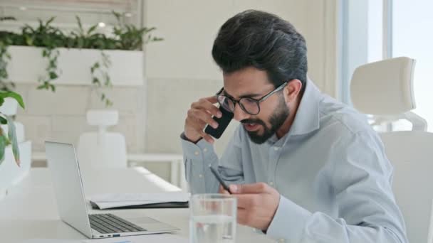 忙しいマルチタスク アラビアのビジネスマンマネージャーコンサルタント インドのイスラム教徒の男話 携帯電話のチェック情報 ノートパソコンの仕事 コンサルティング クライアント スマートフォン ビジネス相談 オフィス — ストック動画