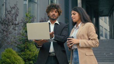 Düşünceli, düşünceli, ciddi, düşünceli iş ortakları Arap iş adamı Hintli iş kadını yöneticiler iş arkadaşları şehirdeki bilgisayara bakarak dizüstü bilgisayar sorununu tartıştılar.