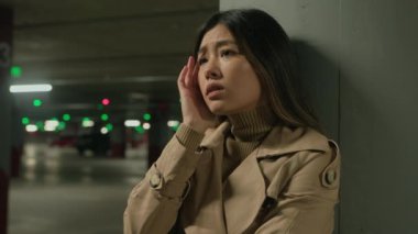Stresli üzgün Asyalı kadın üzgün Çinli Japon kadın yalnız başına araba parkında zor düşünceler depresyonda stres yorgunluğu psikolojik sorunlar yaşıyor.