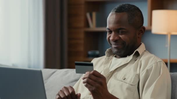 笑顔のアフリカ系アメリカ人男性男性クライアント顧客は インターネットで支払う銀行コンピュータアプリケーションから即座に安全な取引を使用して オンラインでクレジットカード決済を使用します — ストック動画