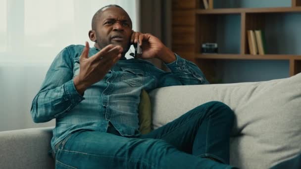 混雑したアフリカ系アメリカ人男性男性ビジネスマン起業家顧客は ソファーの家に横たわる携帯電話で話す スマートフォンを使用して話すサービスに満足しない不快なビジネス会話 — ストック動画