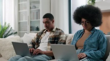 Afrikalı Amerikalı alet bağımlısı çift internet bağımlısı karı koca sosyal medya sanal oyun bağımlısı erkek ve kadın iki dizüstü bilgisayar kullanarak ev ilişkileri probleminde bilgisayarlarla oynuyorlar.