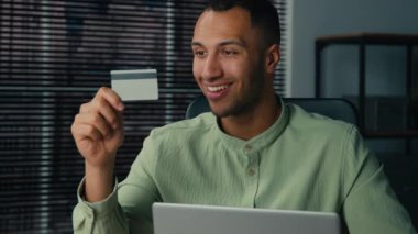 Gülümseyen mutlu Afro-Amerikalı erkek işadamı müşteri uzaktan kredi kartı ödemesi yapıyor. Bilgisayara veri girişi yapıyor. Çevrimiçi mağazaya ödeme başarıyla yapılıyor.