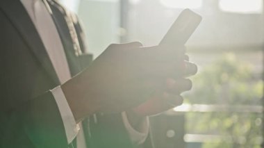 Güneş ışığında akıllı telefon cihazına yazı yazan erkek elleri kapatın. Kırpılmış görünüm tanınmayan Afro-Amerikalı iş adamı cep telefonu şirketi online uygulama ağı mesajları tutuyor.