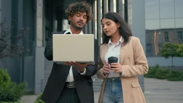 都市のラップトップを指す話をする2人のビジネス同僚 アラビアの従業員の女性 スタートアッププロジェクトの作業を協力して インドの男の戦略を議論するコンピュータを見てブレインストーミング — ストック動画