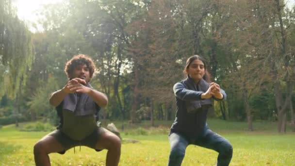 在公园自然户外运动中 这对活跃的夫妇一起做蹲式锻炼 强壮的阿拉伯男子男子和印度女子运动员男子女子健康的生活方式适合蹲着 — 图库视频影像
