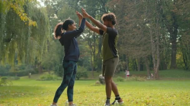 在公园里 一对阿拉伯夫妇在户外和一个女人在一起 男人在公园里 体育男 女朋友 运动员在做冲刺训练 在大自然中做高五的姿势 友情达到团队精神的支持伸展 — 图库视频影像