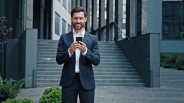 Kafkasyalı başarılı iş adamı girişimci yönetici yönetici erkek CEO cep telefonu kullanıyor e-posta tarama iş haberlerini sosyal ağda şehir merkezindeki akıllı telefondan kontrol ediyor