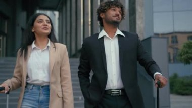Hintli iş kadını, Arap iş kadını, etnik iş arkadaşları, seyahat çantalı seyahat çantalı gezginler, şehirde yürüyen bavullar, havaalanı terminalinden arkadaşça gülümseyen bir gülümseme bırakın.