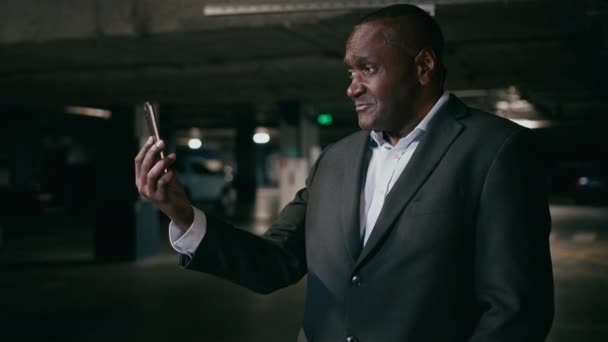 愤怒的不满意的有压力的非洲商人企业家用手机在黑暗的地下停车场讲话用智能手机网络摄像头解决问题冲突压力 — 图库视频影像