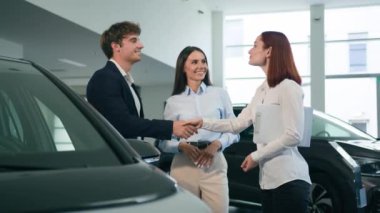 Satıcı kadın tacir kadın tüccar müşterilere yeni bir araç gösteriyor mutlu bir çift araba satın alıyor araba galerisi satıyor aile alışverişi yapıyor danışmanlık anlaşması satın alıyor