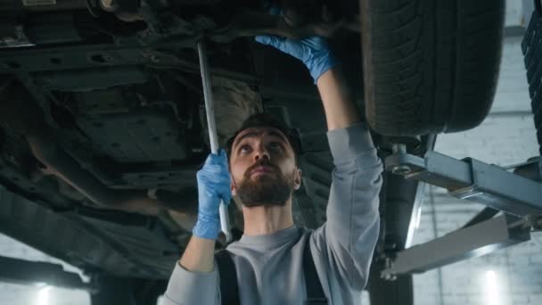 Kaukaski Człowiek Mechanik Pracujący Pod Maszyną Podnoszenia Samochodów Garażu Pomocą — Wideo stockowe
