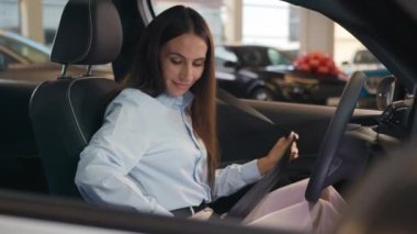 Beyaz müşterili kadın alıcı kız müşteri lüks bir arabada oturuyor emniyet kemerini takıyor galeriyi ziyaret ediyor otomobil kirası test sürüşünü seçiyor araç seçiminin tadını çıkarın