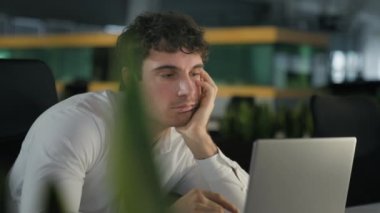 Kafkasyalı yorgun işadamı ofiste dizüstü bilgisayarla sıkıcı bir iş yapıyor. Yorgun, tembel, sıkılmış iş adamı işveren, iş yerinde çalışan, bilgisayar erkek yöneticisi, tükenmiş yorgunluk, aşırı çalışma.