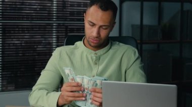 Serious focused african american man male guy businessman bank employee accountant financial consultant counting stack money dollars banknotes in office at workplace calculating cash budget investment