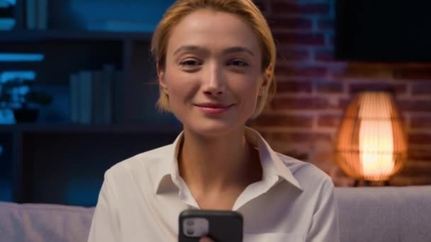 Kaukasische Unbeschwerte Frau Mit Handy Lächelt Nachts Die Kamera Hause — Stockvideo
