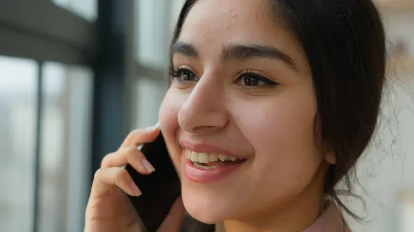 stock image Close up head shot Arabian girl talking mobile phone near window smiling female businesswoman lady speak business call Indian woman at home office calling laughing talk smartphone distant conversation