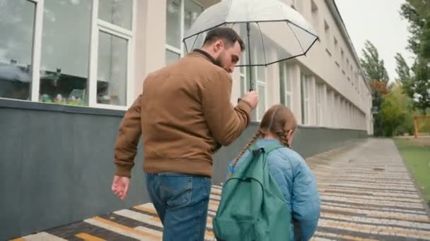 父女俩一起走着雨 聊着快乐的家庭城市街道外面爸爸伞式学校外的女生学习女生书包回家雨天小学课程学习教育 — 图库视频影像