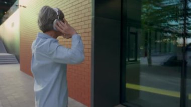 Mutlu Kafkasyalı Kafkasyalı iş kadını olgun 50 'li yaşlardaki yaşlı kadın şehir merkezinde orta yaşlı kadın işkadını dansında dinlenen kulaklıkla müzik dinliyor ve eğleniyor.