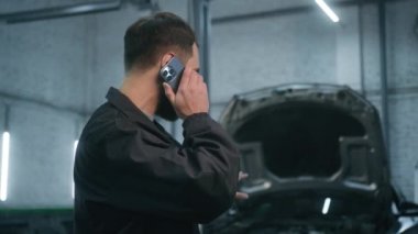 Otomobil tamircisi Kafkasyalı adam teknik işçi araç tanılama müdürü bakım mühendisi tamir servis istasyonunda çalışıyor müşteri cep telefonu siparişi otomobil ayrıntıları makine